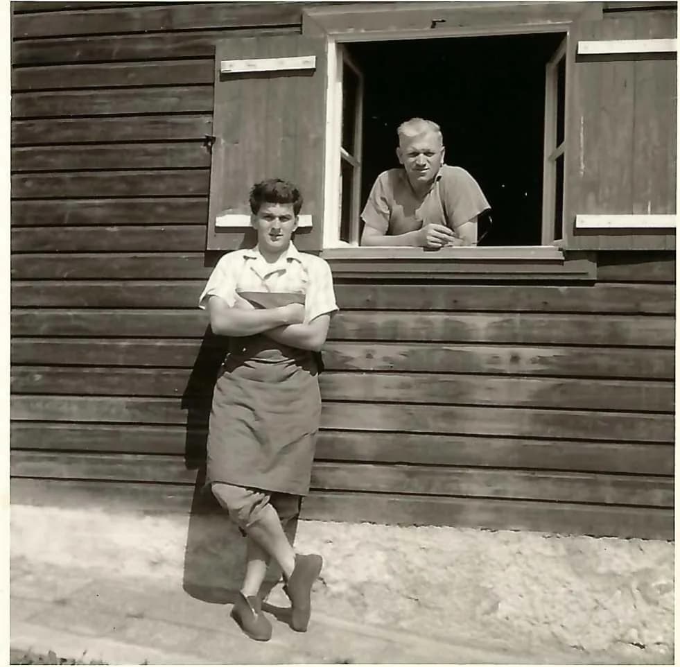 Zwei Schuhmacher der Familie Zunner an der Werkstatt am Maxtorgraben, ein junger Mann in Schürze und ein älterer Mann am Fenster, um 1940